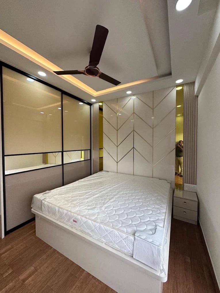 Bedroom with a herringbone panelled bed wall and a sliding wardrobe