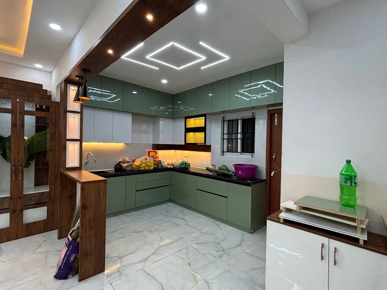 Kitchen with sage-green gloss units, linear ceiling lights and a timber-clad breakfast counter