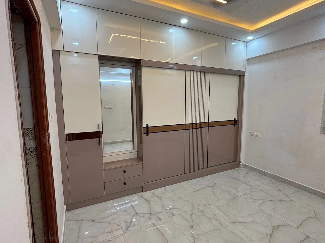 Bedroom wardrobe wall with loft units, sliding shutters with a fluted inlay and a built-in dresser with mirror